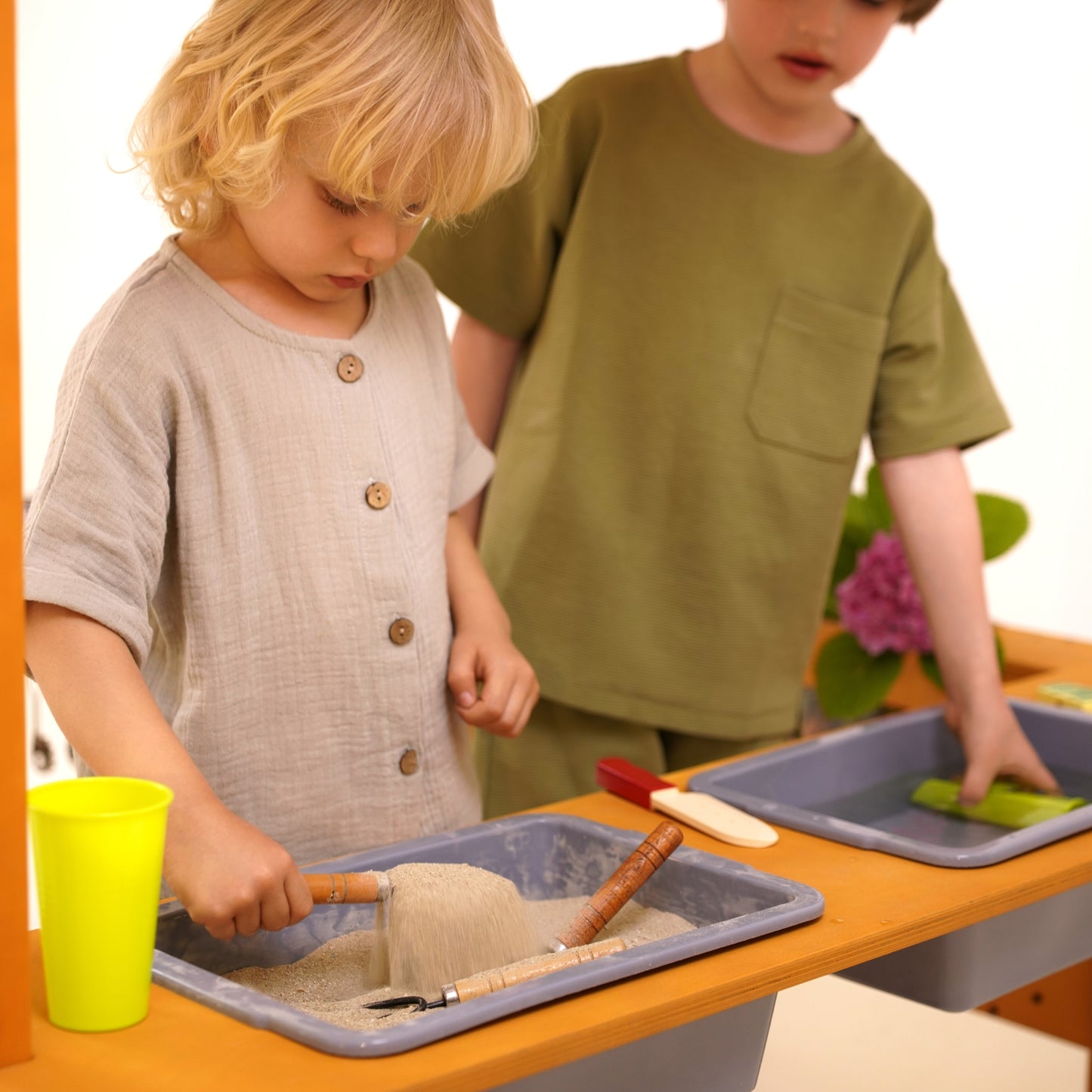Child scooping sand in the Avenlur Sumac mud kitchen with water and sand bins