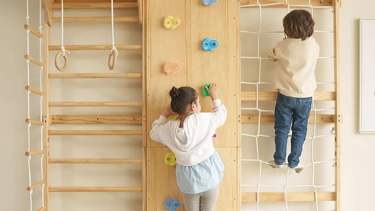 Children playing on the Avenlur Walnut wooden climbing wall gym in a playroom
