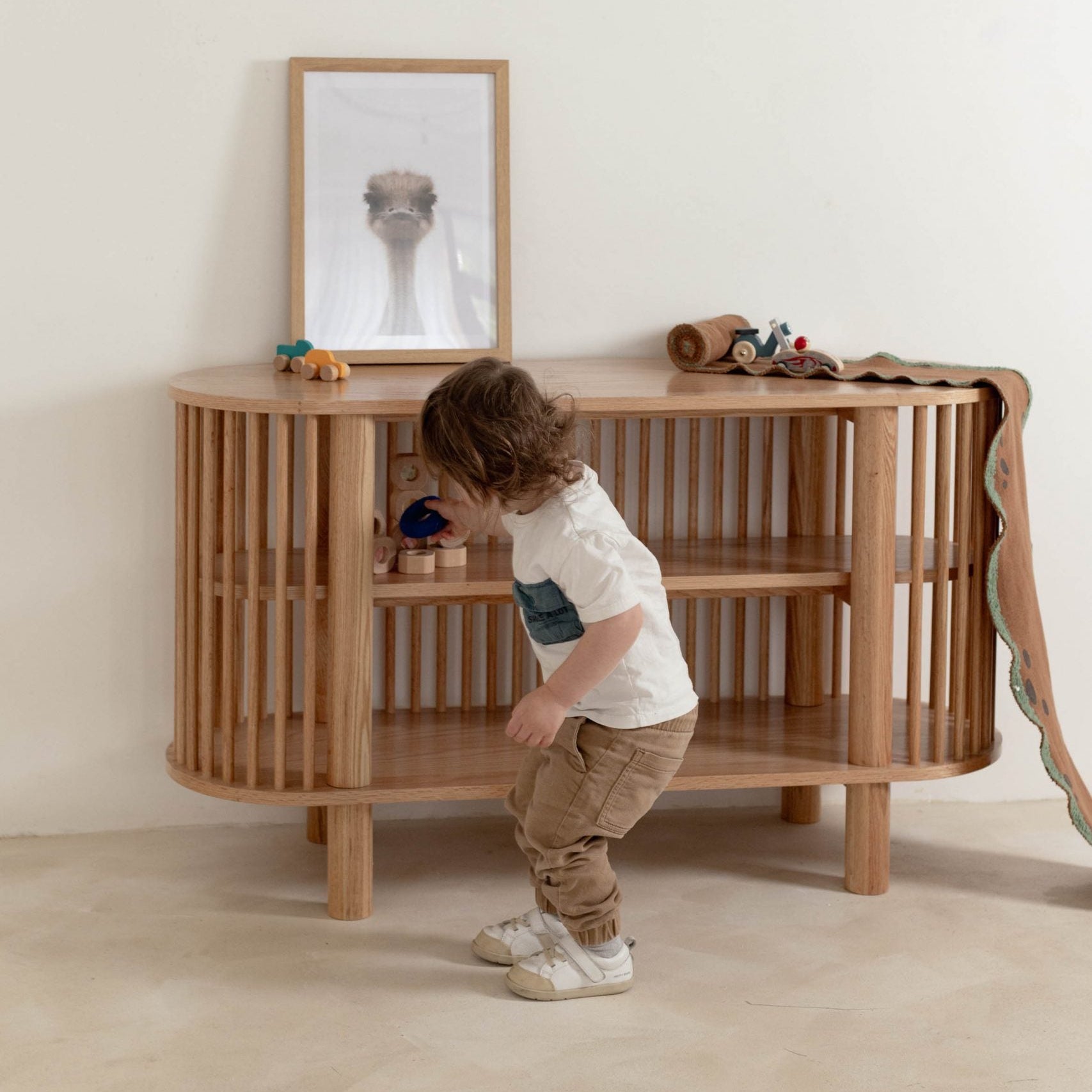 Child playing with a wooden crib in a minimalistic room.