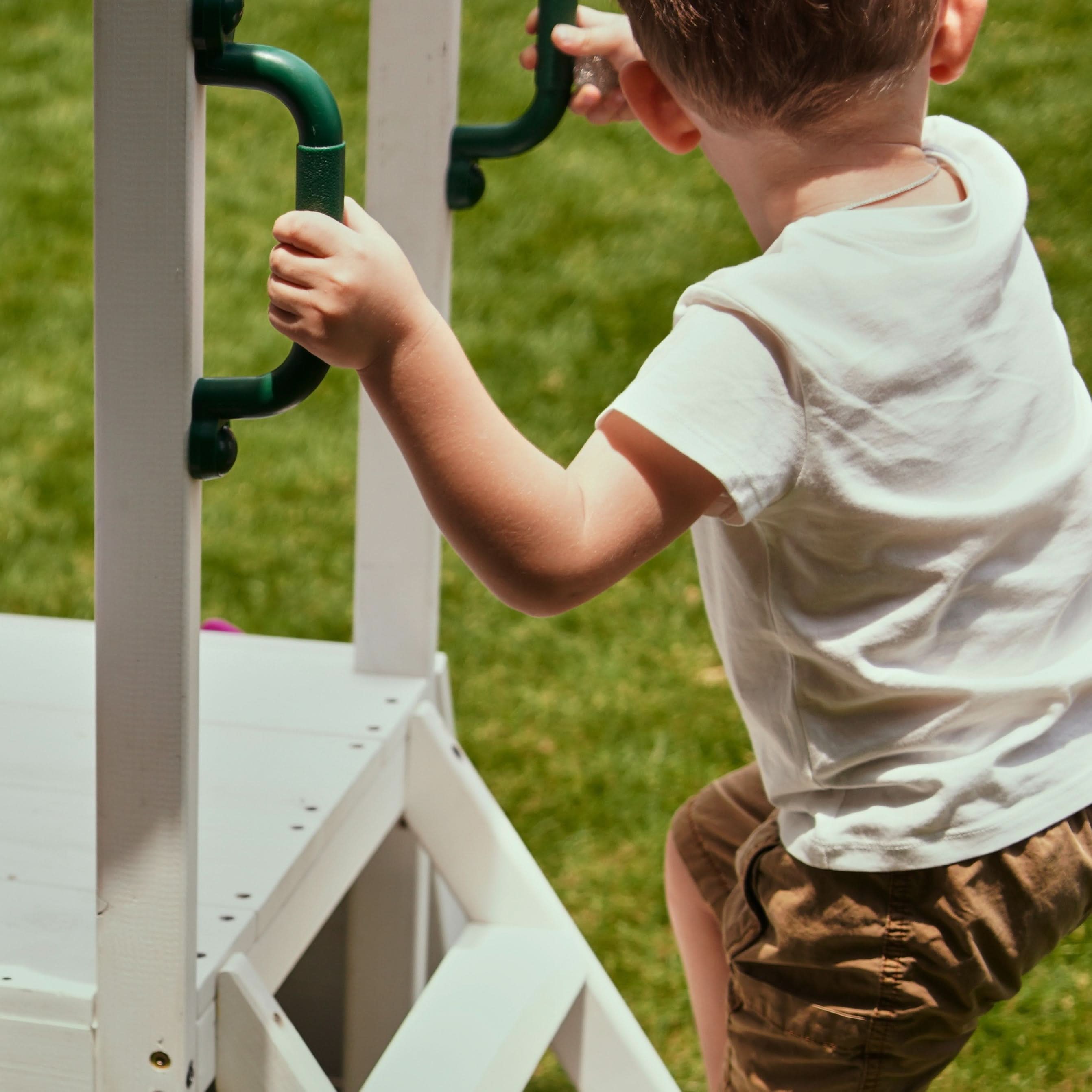 Toddler climbing the Avenlur Aloe playhouse ladder using ergonomic green grab handles