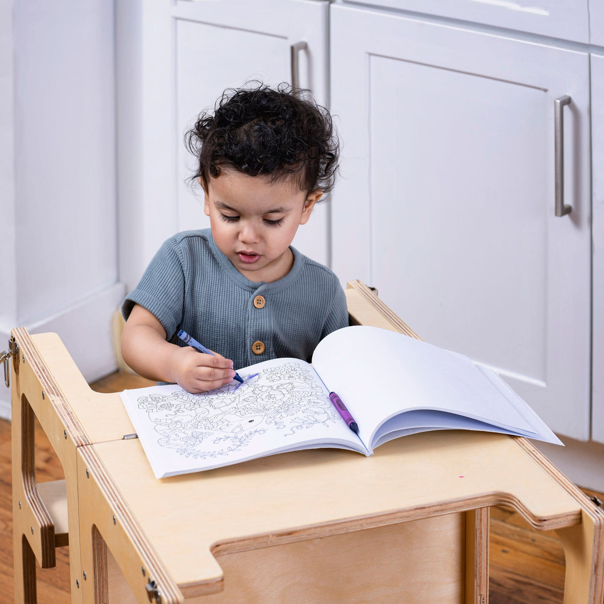 Child using the Avenlur Date kitchen helper tower to wash vegetables