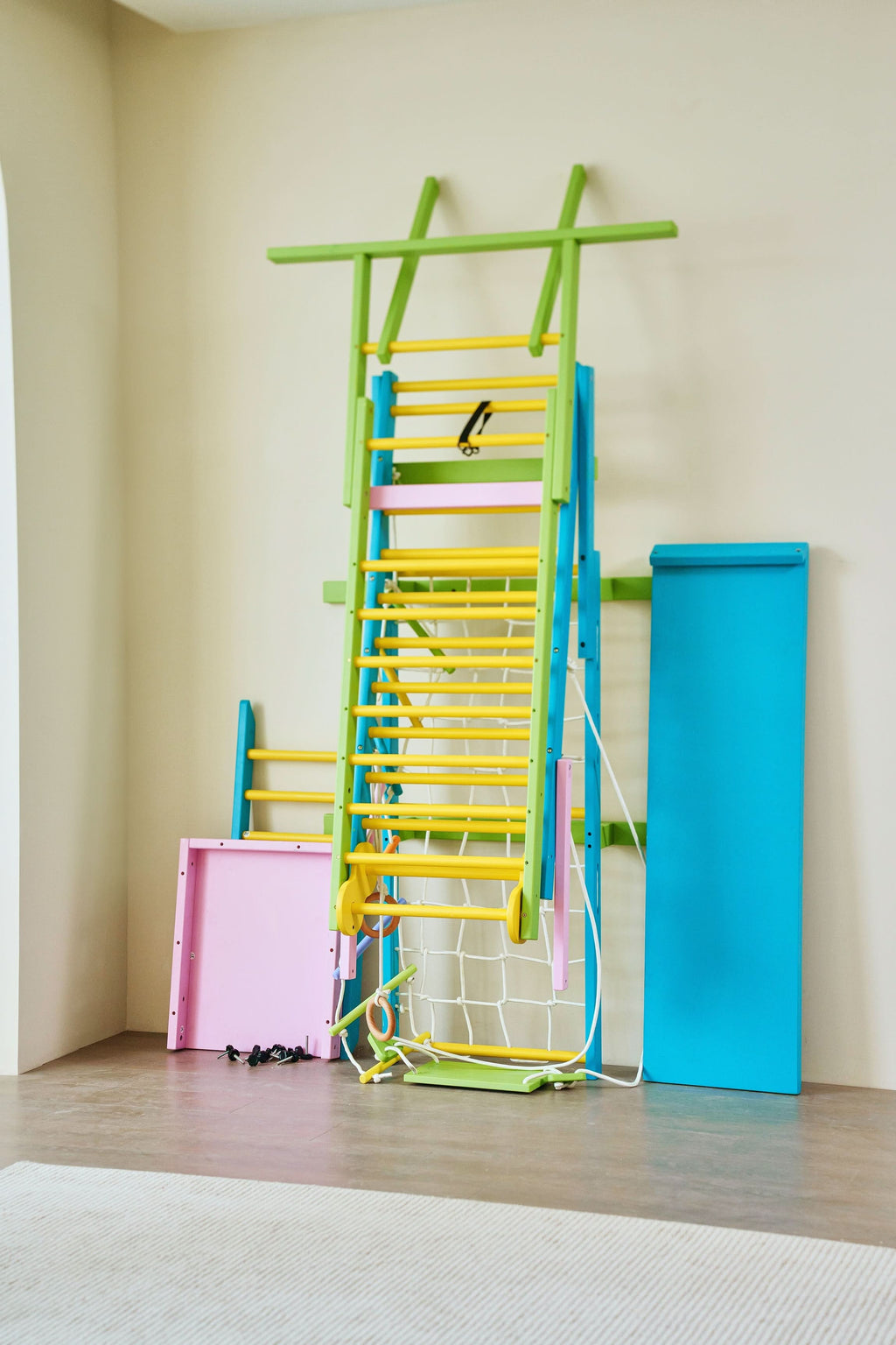 Child hanging from the monkey bars on the Avenlur Grove rainbow indoor gym for kids