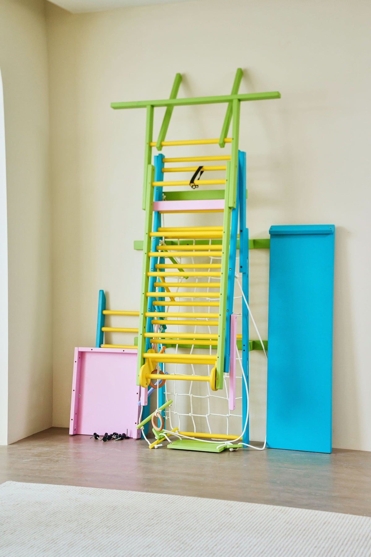 Child hanging from the monkey bars on the Avenlur Grove rainbow indoor gym for kids