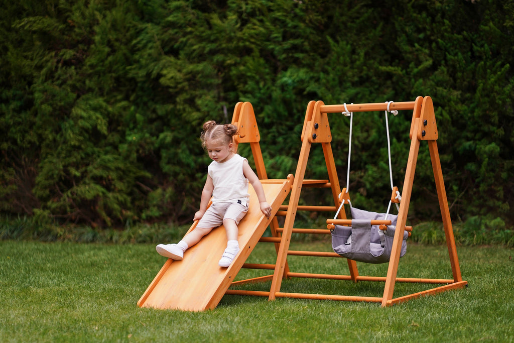 Toddler on the Avenlur Juniper outdoor climbing toy in the yard