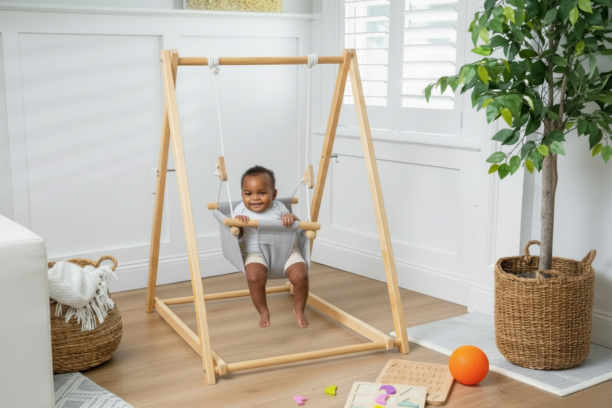 Toddler on the Avenlur Spruce baby and toddler swing set in a bright playroom
