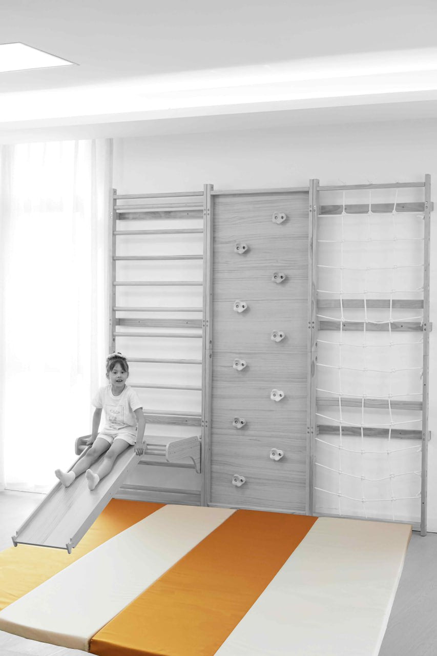 Avenlur Walnut playset mat in front of the Walnut 9-in-1 Swedish ladder wall gym