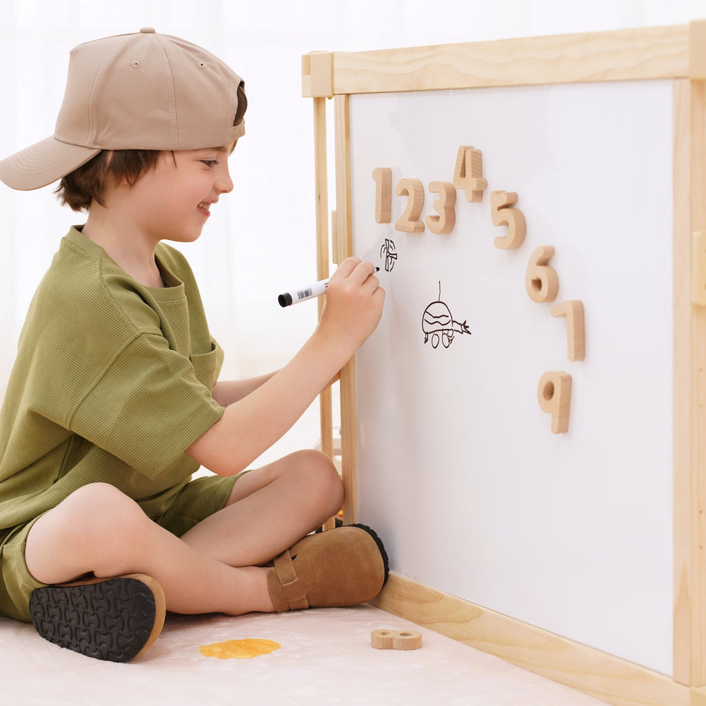 Toddler drawing on the flip-side whiteboard panel of the Avenlur wooden playpen