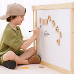 Toddler drawing on the flip-side whiteboard panel of the Avenlur wooden playpen