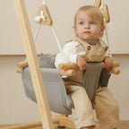 Toddler sitting in the Avenlur gray cotton canvas hammock swing seat hanging from a wooden swing stand