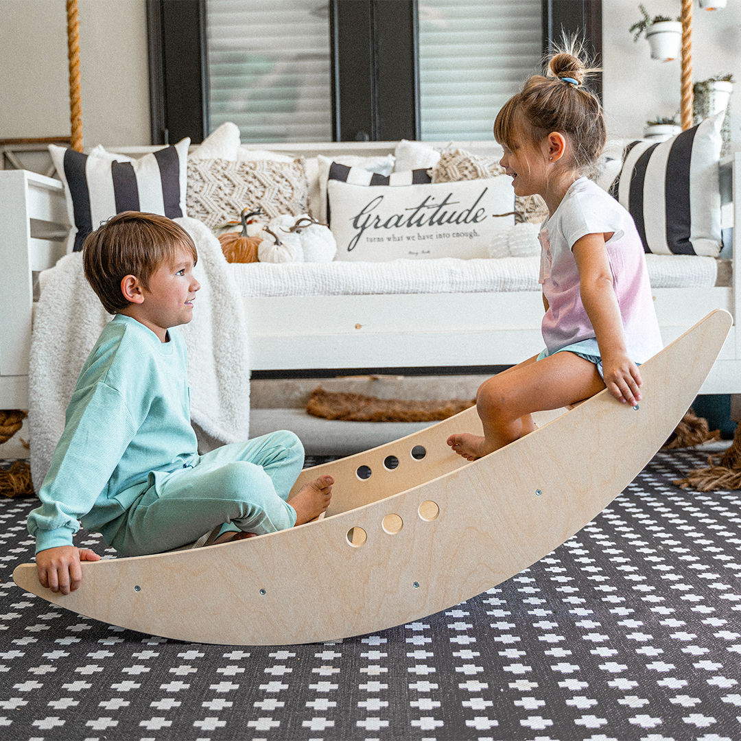 Children rocking together in the Avenlur Rowan 2-in-1 wooden rocking boat in a bright playroom