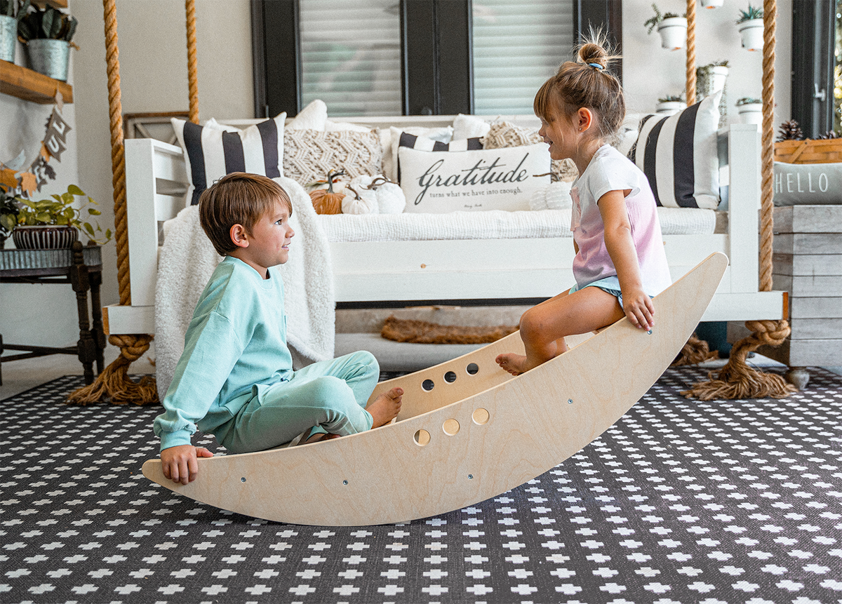 Children rocking in the Avenlur Rowan wooden rocking boat in a Montessori playroom
