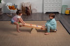 Toddler rocking on the Avenlur Willow wooden rainbow seesaw